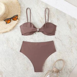 Flat lay of brown high waist bikini set with metal buckle detail and beach accessories