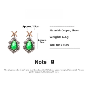 Macro shot of vintage teardrop earrings with green zircon and copper flower stud