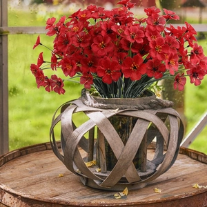 Close-up of artificial red violet flowers with yellow stamens in a rustic wooden basket