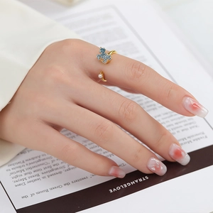 Detail of gold rotatable flower ring with blue glitter horse and white pearl accent