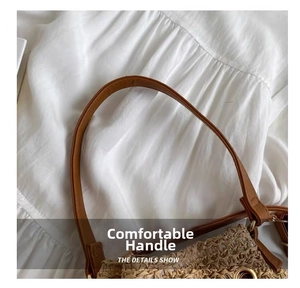 Detail of straw woven bucket bag showing brown PU leather handle stitching and texture