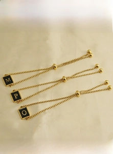Detail of adjustable gold stainless steel bracelets with square initial M P O pendants