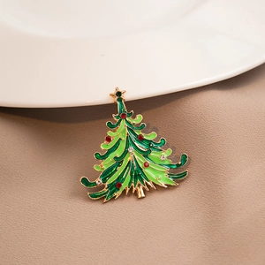 Detail view of a green enamel Christmas tree brooch with crystals on a fabric background