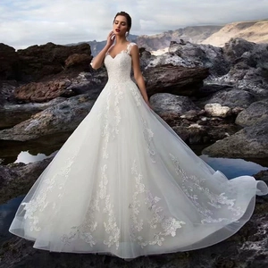 Elegant sleeveless A-line white wedding dress with lace floral embroidery on coastal rocks