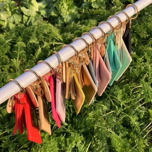 Close-up of colorful leather card holders with decorative tassels and gold metal rings
