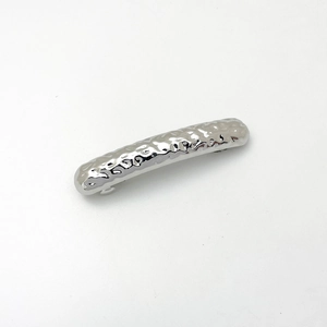 Detail shot of silver metallic hair clip featuring elegant hammered texture and glossy finish