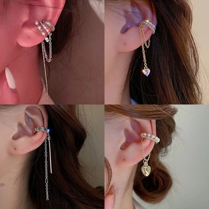 Detail of silver ear cuffs with cubic zirconia, pearls, heart pendants and tassels