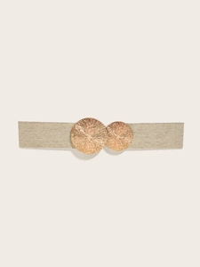 Detail of wide elastic waist belt with textured gold circular buckle on beige fabric