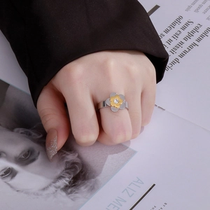 Detail view of a two-tone floral titanium ring with a sparkling zircon center on a model hand