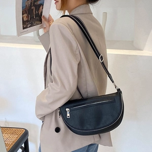 Women black crescent crossbody waist bag with wide adjustable strap worn on beige blazer