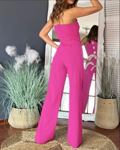 Detail of rose pink strapless jumpsuit featuring side gold buttons shown in a mirror