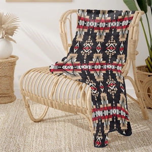 Detail of soft flannel throw blanket with tribal geometric patterns on a rattan chair