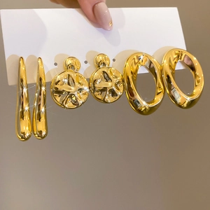 Macro view of three-pair gold earring set with smooth, textured and twisted designs