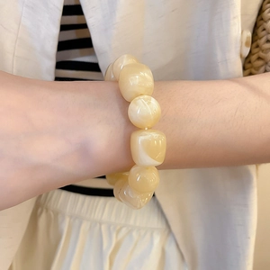 Gros plan d'un bracelet en perles d'acrylique beige avec texture marbrée sur un poignet