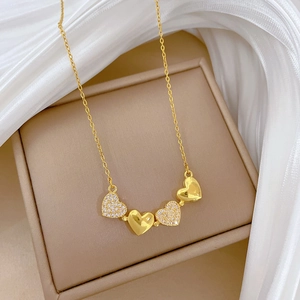 Detailed close-up of gold titanium steel necklace with alternating heart pendants