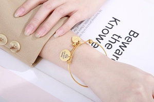 Close-up of golden adjustable wire bracelet with engraved Love you Grandma heart pendants