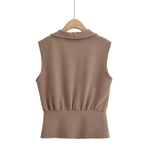Detail of brown textured sleeveless vest with waist pleats on a wooden hanger