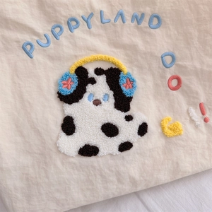 Detail of cute puppy chenille embroidery with Puppyland text on beige canvas tote bag