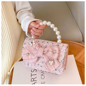 Detail of pink tweed girl's handbag with large bow and elegant pearl bead handle