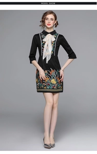 Detail of colorful floral embroidery and large white bow on black dress