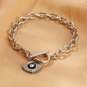 Macro shot of silver OT buckle chain bracelet with Evil Eye charm on orange satin