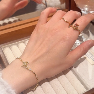 Detail of 18k gold plated butterfly bracelet and zircon wave ring on model hand