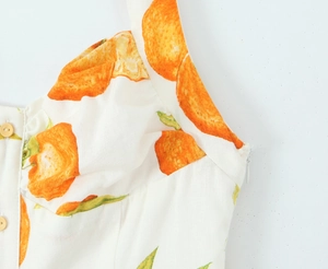 Detailansicht des Orangendrucks mit Holzknöpfen und Reißverschluss am weißen Leinenkleid