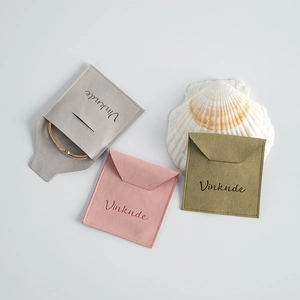Detalle de sobres de microfibra para joyas en gris rosa y verde con decoración