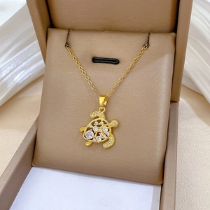 Detail of a hollow turtle pendant necklace in gold finish with white zircon inlay