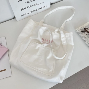 Sac cabas blanc en toile avec broderie de nœud rose et bandoulières vue à plat