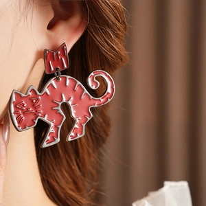 Close-up of model wearing red cartoon cat stud earrings with silver crown detail