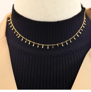 Dettaglio della collana girocollo d'oro con ciondoli rettangolari martellati su maglia nera
