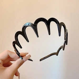 Close-up of black plastic wavy headband with comb teeth design for secure hair styling