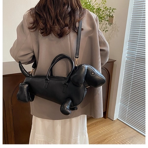 Close-up of a black dachshund-shaped leather handbag with gold hardware and shoulder strap