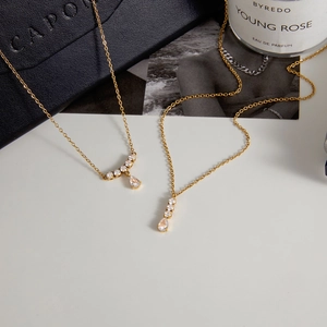 Detalle de collares bañados en oro con colgantes de circonita junto a caja de lujo
