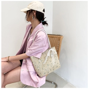 Detail of straw tote bag with white lace ribbon and delicate floral embroidery