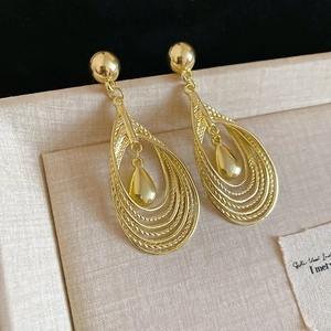 Macro shot of tiered hollow teardrop earrings in gold with a vintage polished finish