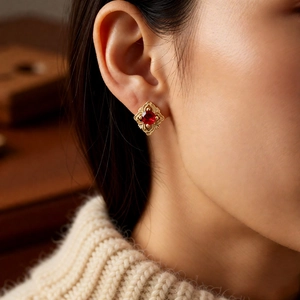 Gros plan d'une boucle d'oreille vintage avec pierre rouge et cadre doré portée par modèle