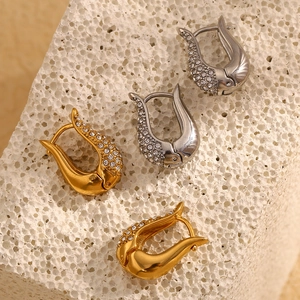 Detail of U-shape gold and silver earrings with zircon crystals on white stone base