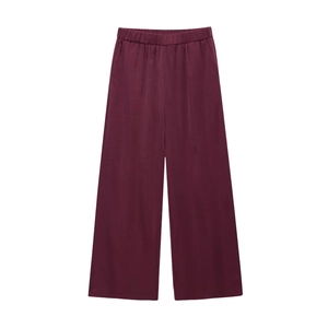 Detail of burgundy wide-leg trousers featuring elastic smocked waist and draped fabric texture