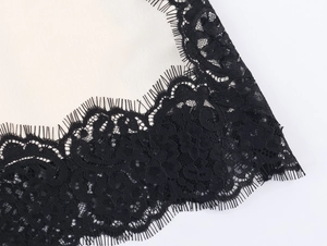 Close-up of black eyelash lace stitching on off-white satin fabric with floral patterns