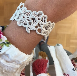 Detail shot of white lace floral cuff bracelet featuring hollow embroidered flower patterns