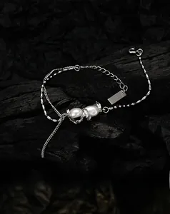 Detail of a double-layered silver bracelet featuring unique baroque pearls on dark texture