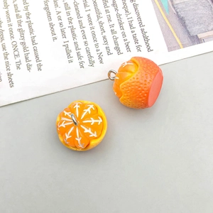 Close-up of two cute orange resin bread charms with metal rings on gray background
