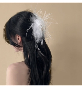 Detailed side view of elegant white ostrich feather hair clip worn on wavy black hair