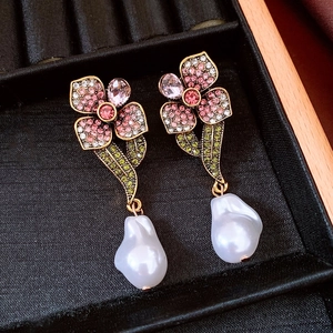 Détail macro de boucles d'oreilles fleur perle avec cristaux et finition dorée