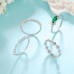 Detalle de un juego de cuatro anillos de plata con piedra esmeralda y motivo de hoja