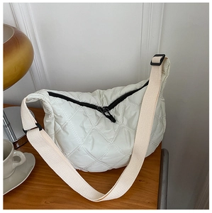 Quilted white crossbody bag with lattice stitching shown on a cozy wooden table set