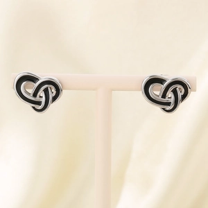 Detail of vintage heart-knot pearl earrings in silver finish with black enamel inlays