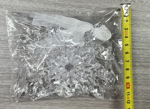 Detailed view of clear acrylic snowflake and icicle ornaments with white hanging ribbons